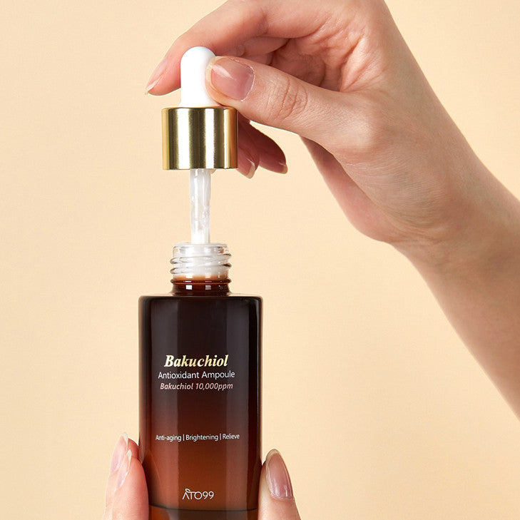 Одна рука тримає пляшечку, інша дістає піпетку з ампули ATO99 Bakuchiol Antioxidant Anti-Aging Brightening Ampoule на оранжевому фоні.