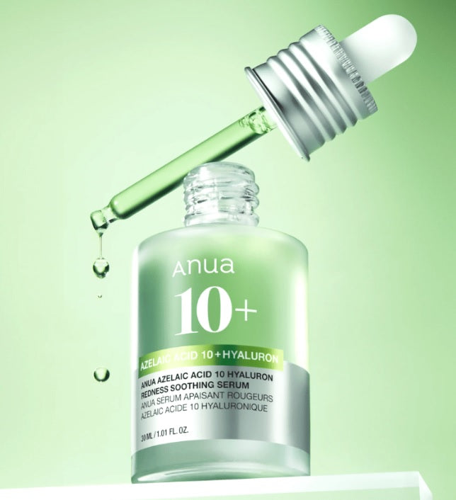 Відкритий флакон сироватки Anua Azelaic Acid 10 Hyaluron Redness Soothing Serum стоїть на білій поверхні, над ним біла піпетка, з якої витікає зелена сироватка на салатовому фоні.