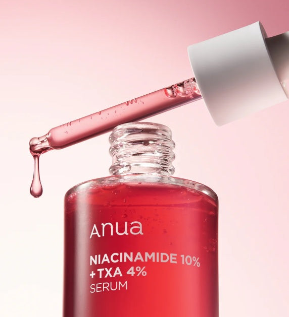 Відкритий флакон сироватки ANUA NIACINAMIDE 10% + TXA 4% SERUM, над ним біла піпетка, з якої витікає червона сироватка на біло-рожевому фоні.