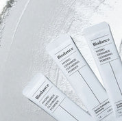 Три саше засобу BIODANCE Hydro Ceramide Cleansing Powder лежать на поверхні, на якій розсипаний порошок.