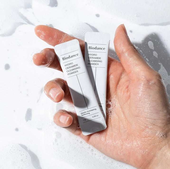 У долоні лежать два саше, рука трохи опущена у воду, і вся у піні.