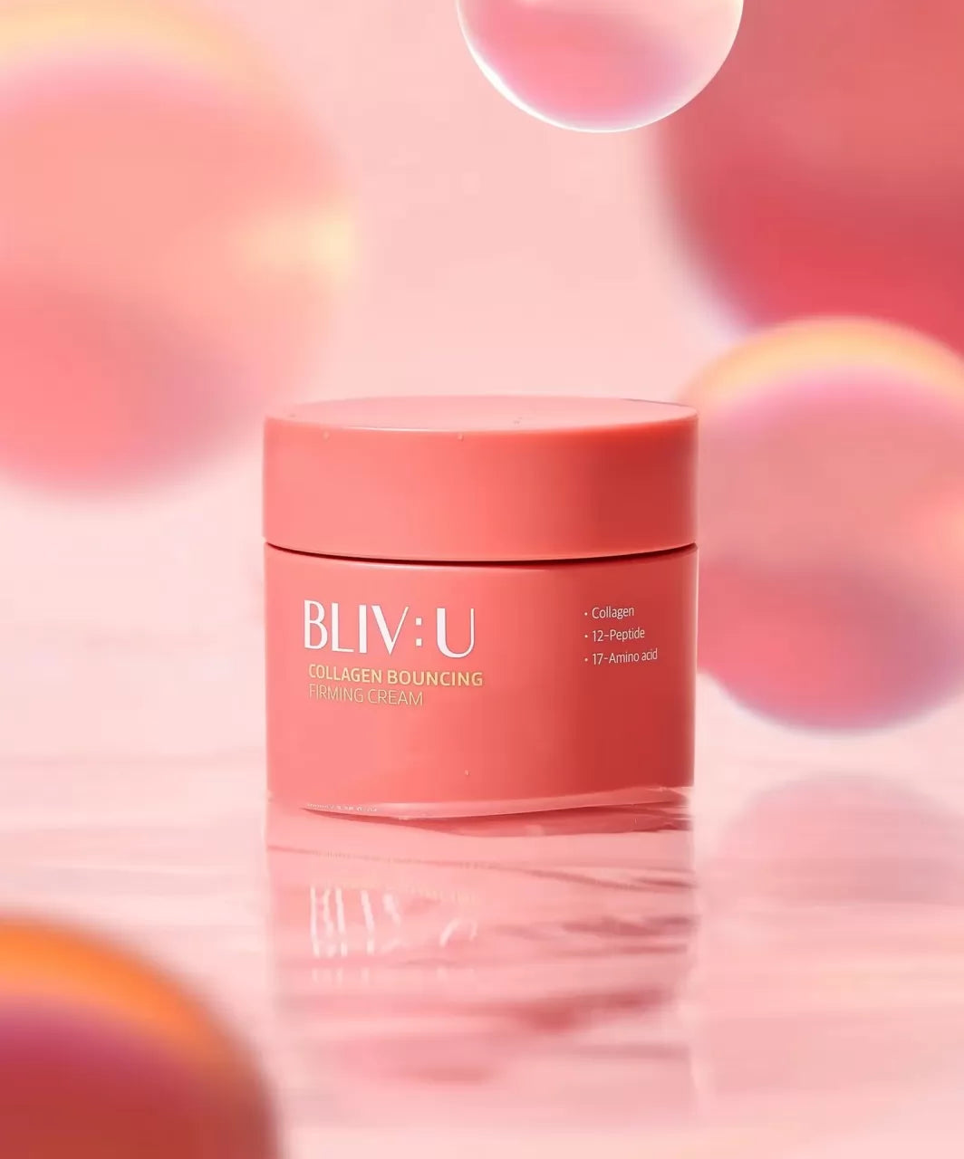 Баночка BLIV:U Collagen Bouncing Firming Cream 80 мл кольору грейпфрута стоїть на рожевому фоні з градієнтними рожевими кульками