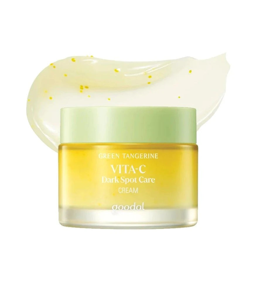 Скляна баночка крему Goodal Green Tangerine Vita C Dark Spot Care Cream з білою кришкою стоїть на білому фоні, на фоні розмазана кремова текстура крему, біло-жовтого кольору з жовтим вкрапленням.
