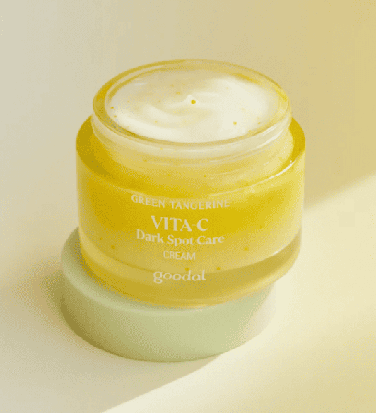 Відкрита баночка крему Goodal Green Tangerine Vita C Dark Spot Care Cream стоїть на кришечці, на жовтому фоні.