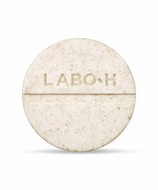 Твердий шампунь LABO-H у зручній круглій формі бежевого кольору з темними вкрапленнями, на білому фоні