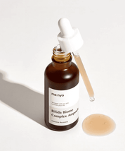 Відкрита пляшечка Ma:nyo Bifida Biome Essence, на якій висить піпетка, з якої витікає есенція.