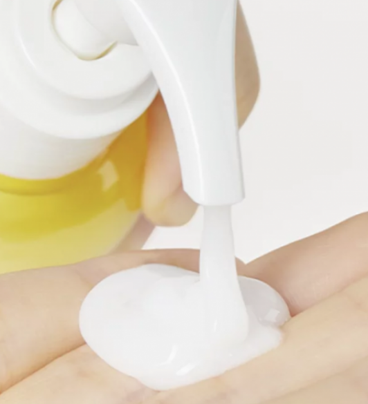 З білого дозатора засобу Ma:nyo Pure Cleansing Milk видавлюється на долоню біла гелева текстура.