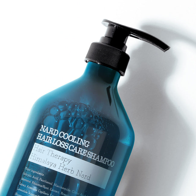 Синій флакон охолоджувального шампуню NARD проти випадіння волосся з чорним дозатором і бульбашками на поверхні