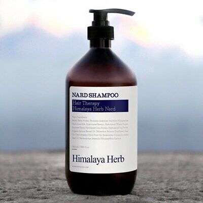 Коричневий флакон з чорним дозатором та темно-синіми написами шампуню NARD на кам'яній поверхні з блакитним фоном, 500 мл