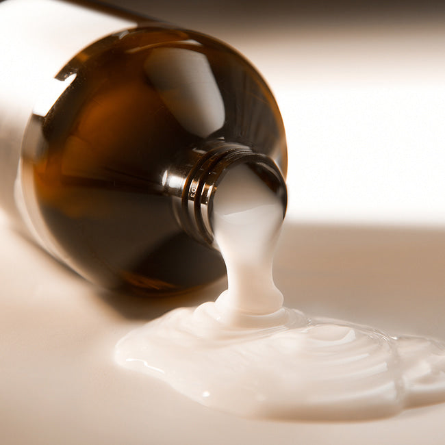 Коричневий флакон без дозатору та чорними написами кондиціонеру NARD Treatment Signature лежить і з нього витікає його біла гелева структура, 500 мл