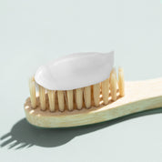 На дерев'яну щітку нанесена зубна паста NARD Whitening Toothpaste