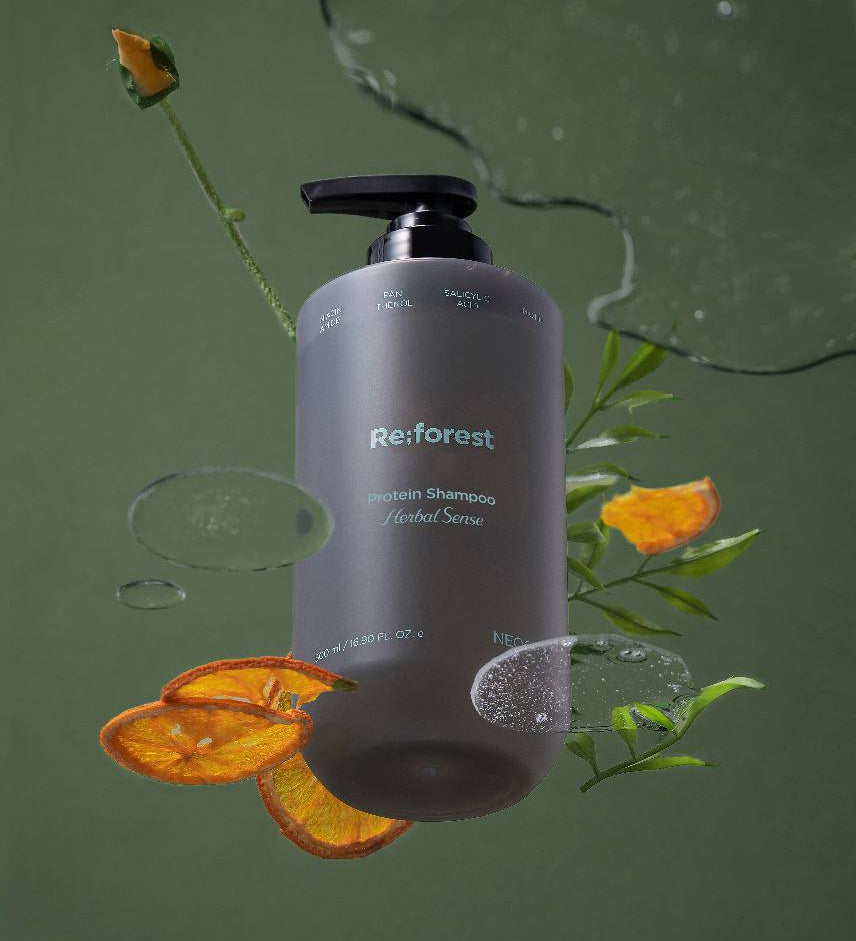 Сіра баночка шампуню Neogen Re:forest з чорним дозатором і поряд розлита гелева текстура шампуню, біля нього шматочки лимону та квітка