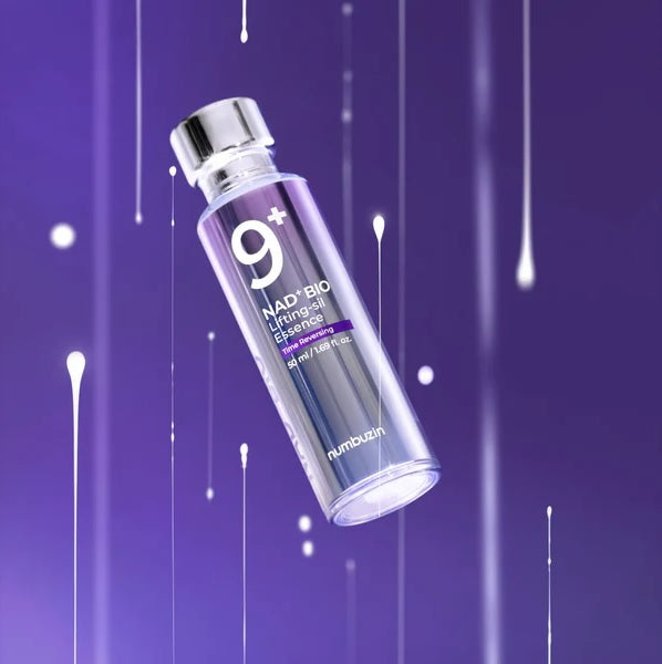 Ампула Numbuzin No.9 NAD Bio Lifting Essence зависла в повітрі на фіолетовому фоні, біля ампули видно краплі, що левітують навколо неї.