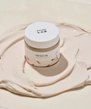 Баночка крему Round Lab Soybean Nourishing Cream стоїть на поверхні, покритій ніжним кремом.