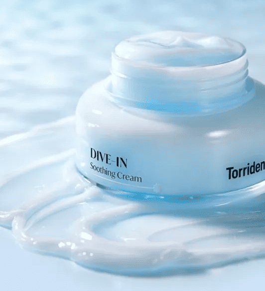 Відкрита баночка Torriden Dive-In Soothing Cream стоїть на поверхні, покритій текстурою крему.
