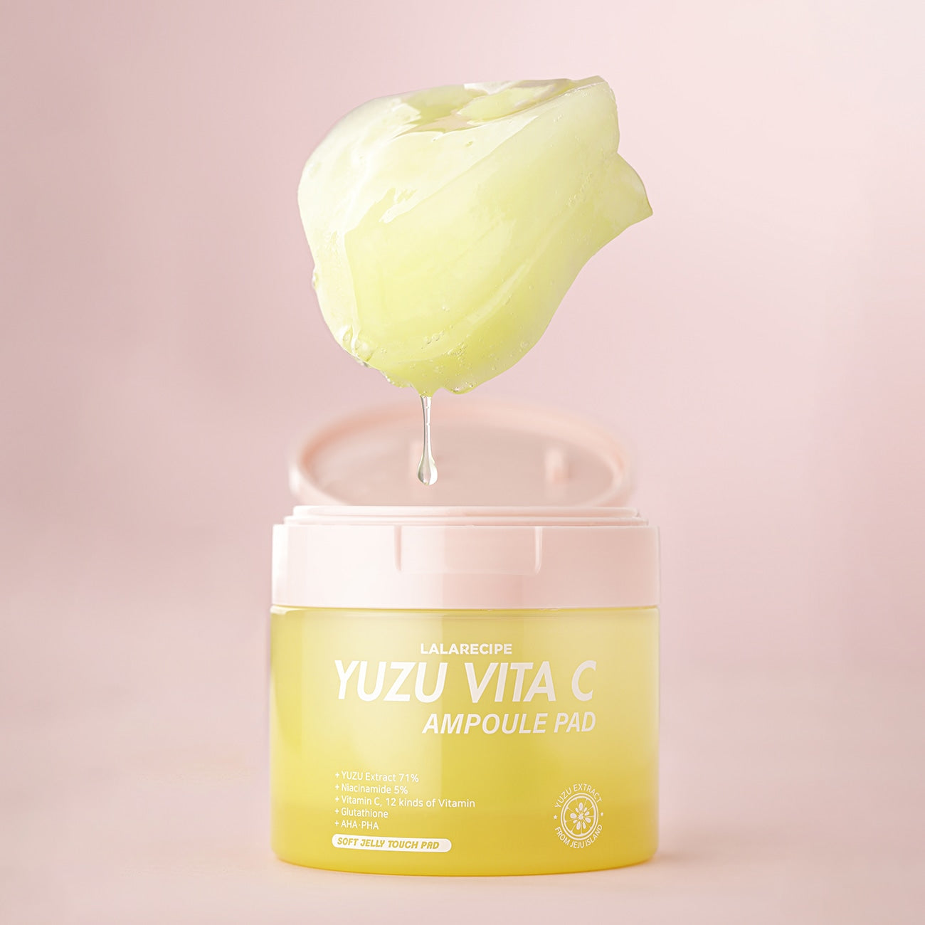 Вітамінні ампульні педи для обличчя з юдзу LALARECIPE Yuzu Vita C Ampoule Pad із краплею сироватки над відкритою баночкою на рожевому фоні