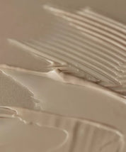 Бежева кремова текстура засобу Aromatica Quinoa Protein Treatment Mask, покриває бежеву поверхню