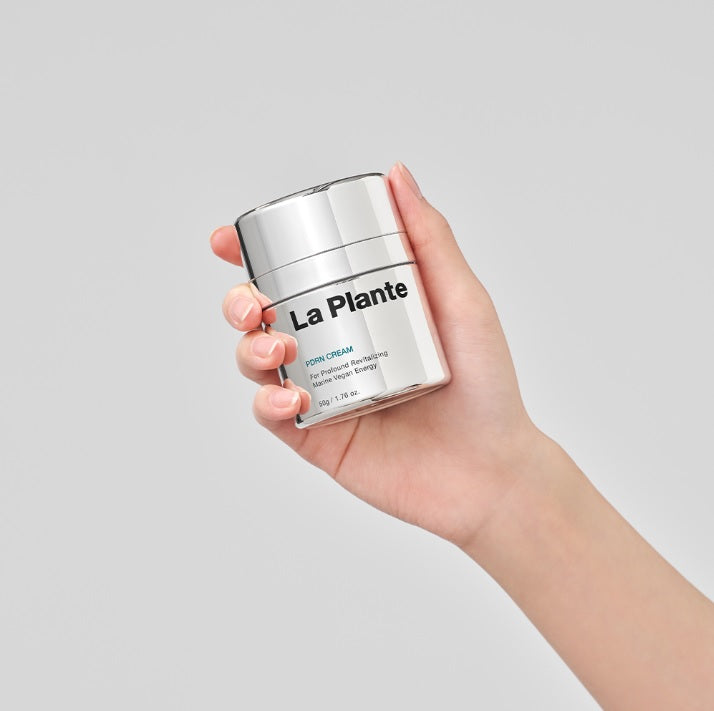 Рука тримає баночку крему LA PLANTE PDRN Cream 50 g на білому фоні.