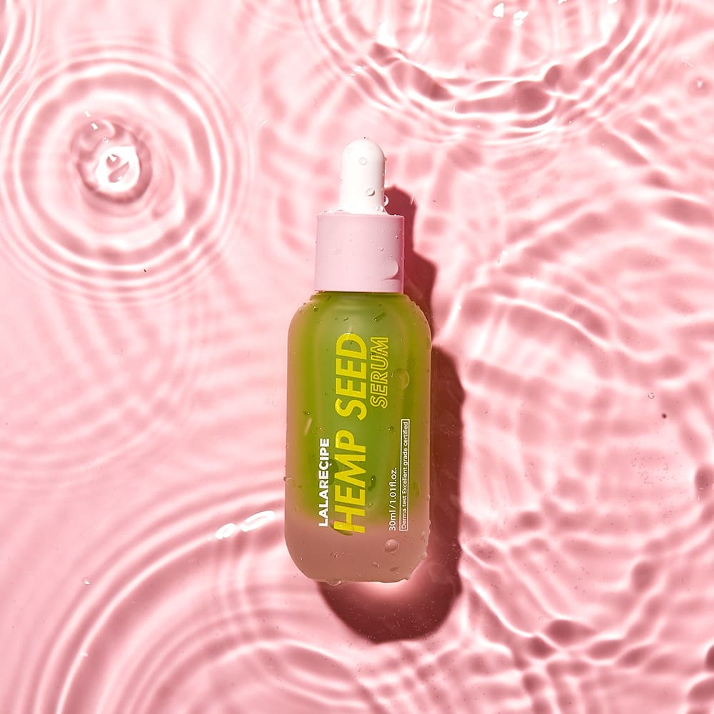 Пляшечка LALARECIPE Hemp Seed Serum з білою піпеткою лежить у воді.