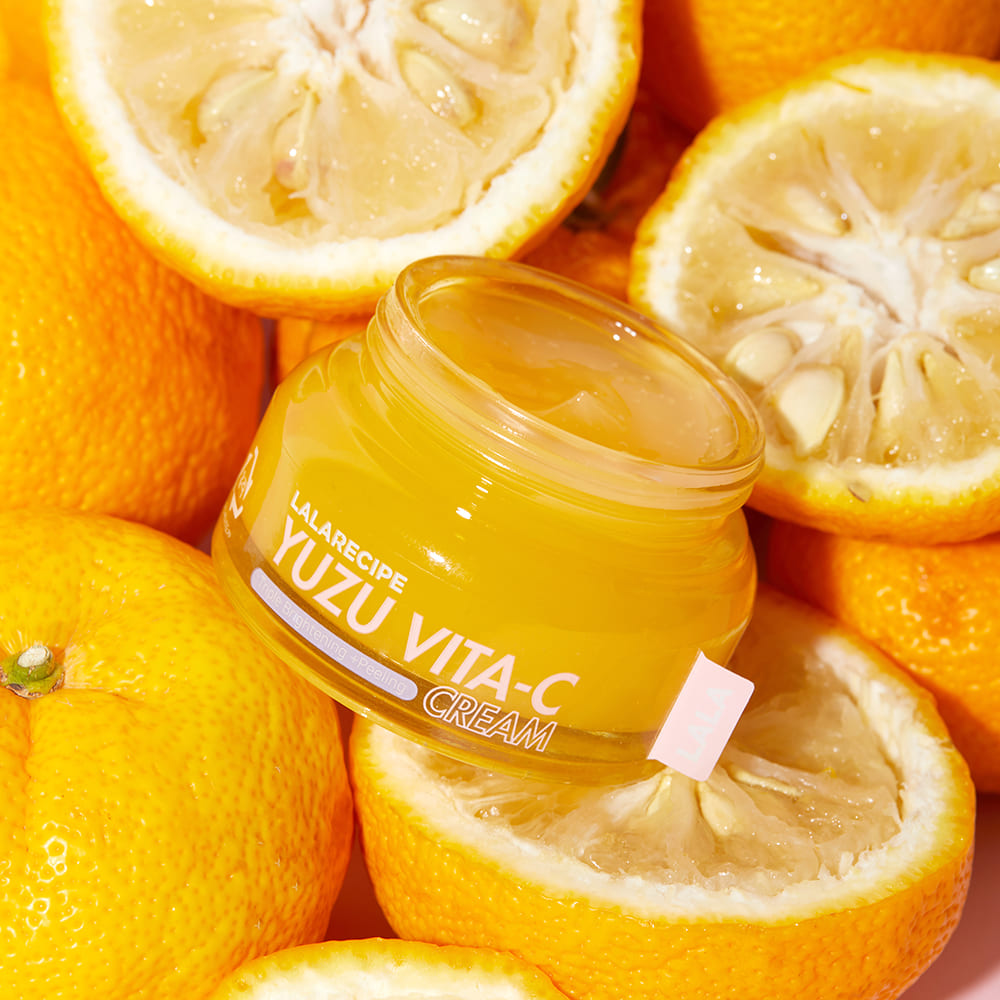 Відкрита баночка крему LALARECIPE Yuzu Vita C Cream лежить на плодах юдзу