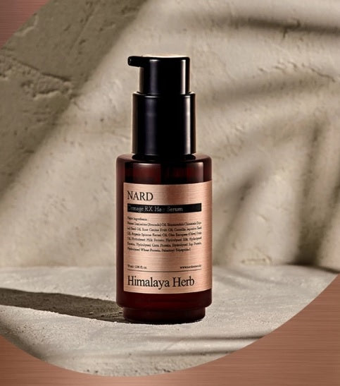 Коричнево-прозора бутилочка з чорним дозатором серуму для волосся NARD Damage RX Hair Serum стоїть на бетонній поверхні.