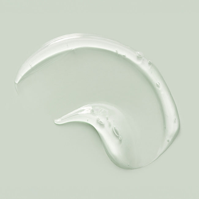 На фото зображена текстура сироватки Bouquet Garni Nard Tea Tree Blemish Calming Serum, нанесена на гладку білу поверхню для демонстрації її консистенції.