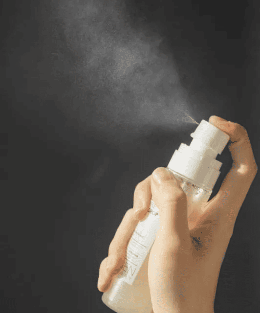 Людина натискає на спрей-дозатор пляшки NEOGEN DERMALOGY WHITE TRUFFLE AMPOULE DROP MIST, розпилюючи міст.