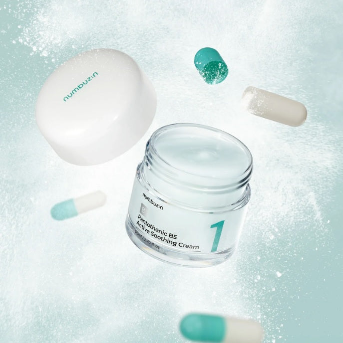 Інсталяція, в якій відкрита баночка крему Numbuzin No.1 Pantothenic B5 Active Soothing Cream з кришкою, що зависає в повітрі, створює ефект легкості. Поряд розташовані відкриті білобірюзові капсули, а навколо них розлітається ніжний білий порошок, що підкреслює концепцію легкості та чистоти.