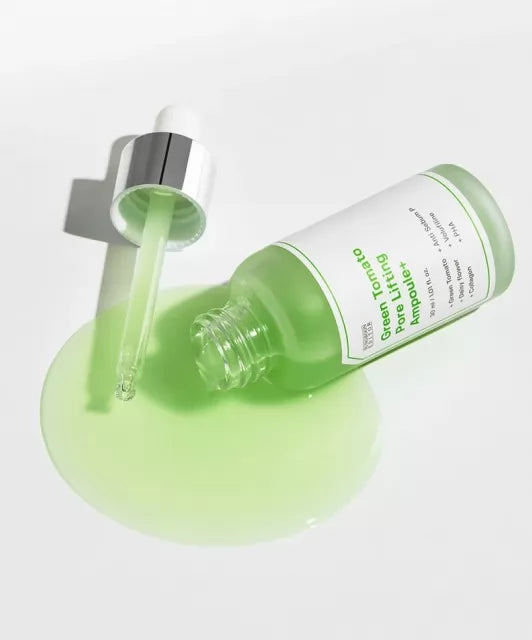 Відкрита зелена ампула SUNGBOON Editor Green Tomato Pore Lifting Ampoule лежить на білій поверхні, з неї витікає сироватка, поруч — піпетка.