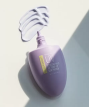 На фото відкритий тюбик Azulene Mild Tone-up Cream, біля нього текстура крему нанесена на білу поверхню.