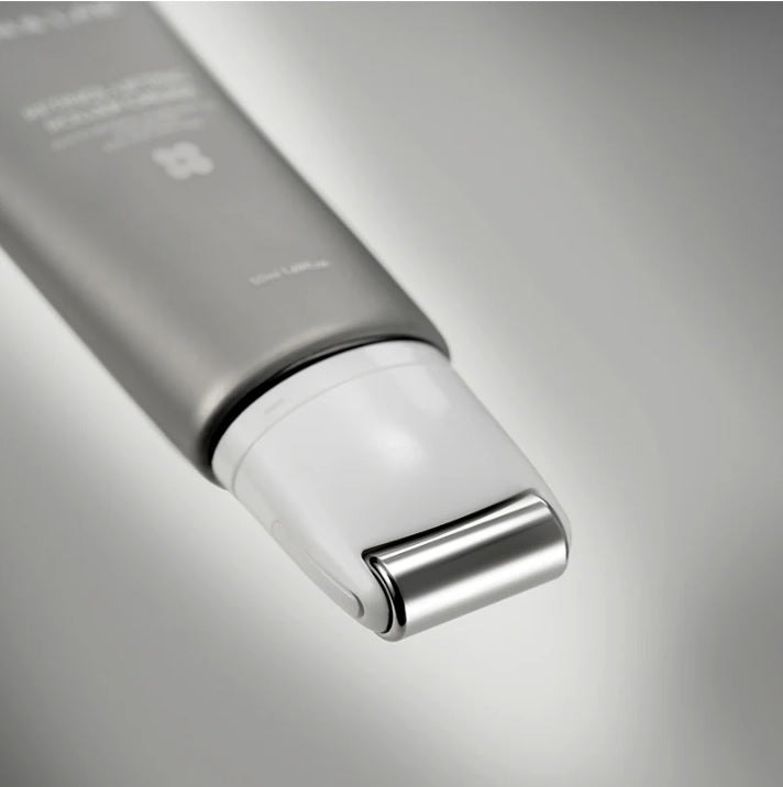 Сірий тюбик з білою роликовою насадкою крему Skin&Lab Retinol Lifting Roller Cream лежить на сірій поверхні.