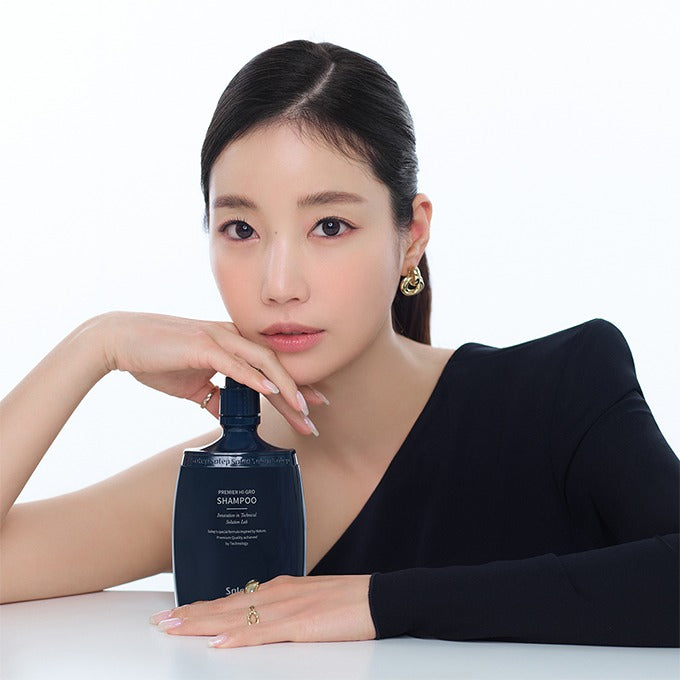 Дівчина азіатської зовнішності поряд з шампунем Solep Premier Hi-gro Shampoo поклала на нього руку