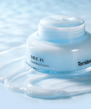 Відкрита баночка Torriden Dive-In Soothing Cream стоїть на поверхні, покритій текстурою крему.