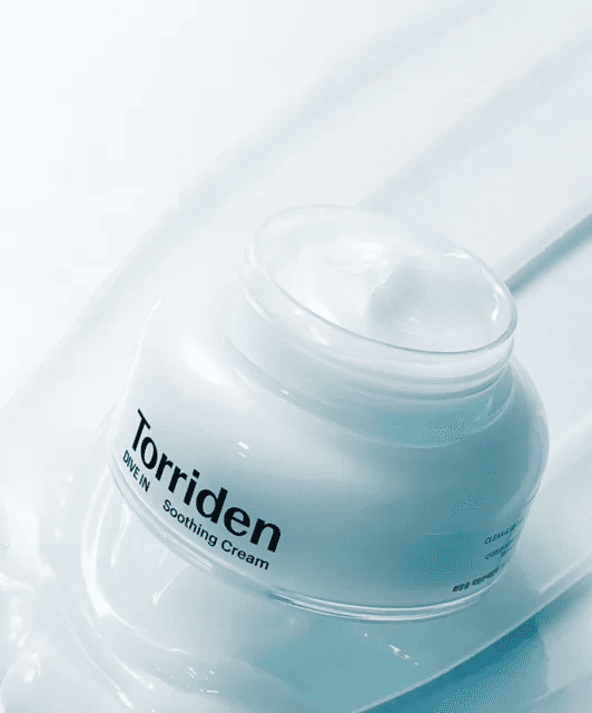 Відкрита баночка крему Torriden Dive-In Soothing Cream стоїть на поверхні, яка нахилена під кутом.