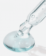 З піпетки Torriden Dive-In Low Molecular Hyaluronic Acid Skin Serum на білу поверхню нанесена блакитна сироватка.