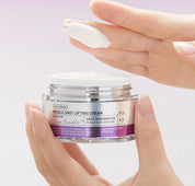 Одна рука пальцями тримає відкриту баночку крему VT Cosmetics Reedle Shot Lifting Cream, а інша легким рухом взяла крем із банки на пальці.